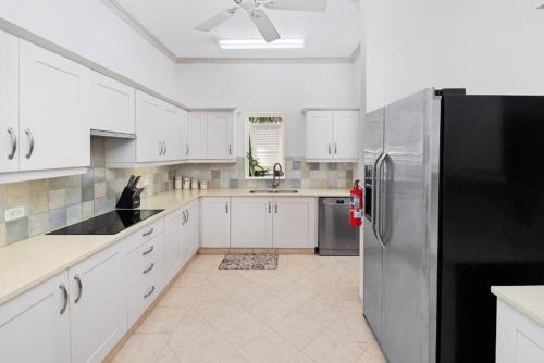 a kitchen with white cabinets and a black refrigerator at Royal Westmoreland - Villa Rosa by Island Villas in Saint James