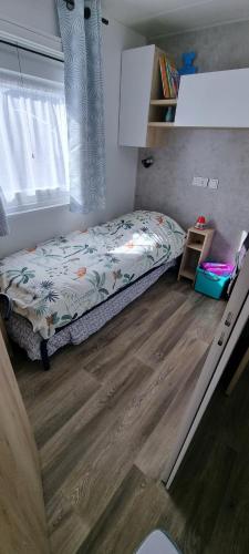 a small bedroom with a bed and a wooden floor at Mobil home dans un camping **** la réserve / siblu in Gastes