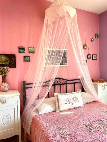 um quarto cor-de-rosa com uma cama e uma rede mosquiteira em Villa Rahati em Kroústas