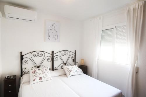 Un dormitorio con una cama blanca con almohadas y una ventana en TU CASA CERCA DEL MAR, en Torrox