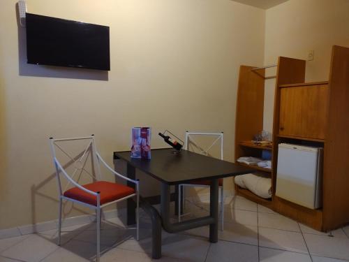 Habitación con mesa, silla y TV. en Motel Kalipso en São José