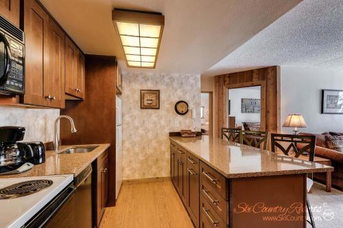 une cuisine avec des placards en bois et un salon dans l'établissement Rustic Charm Meets Comfort, Homey and Affordable with Scenic Mountain Views TE112, à Breckenridge