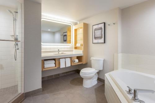 a bathroom with a toilet and a sink and a tub at Delta Hotels by Marriott Grand Okanagan Resort in Kelowna