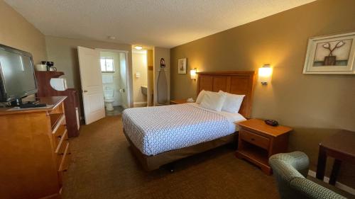 Habitación de hotel con cama y TV en Morgan Inn and Suites Walla Walla en Milton-Freewater