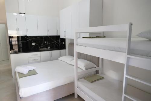 a room with white bunk beds in it at Xhani's Rooms in Durrës