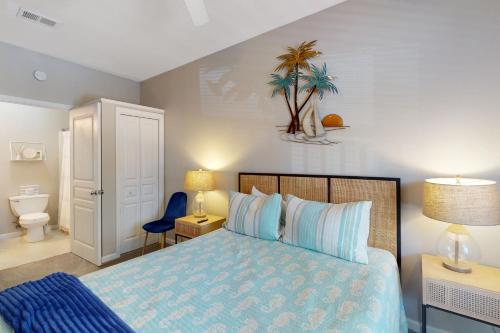 een slaapkamer met een bed en een schilderij met palmbomen aan de muur bij Barataria 203 in Destin