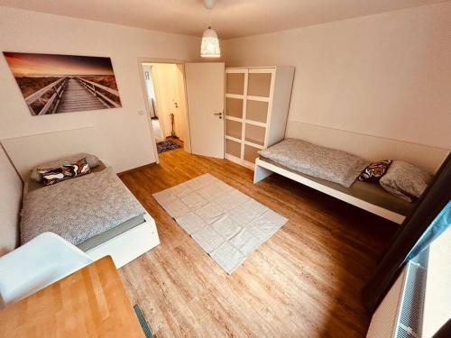a room with two beds and a wooden floor at Schickes Messe Appartement mitten in Essen in Essen