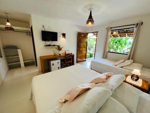 um quarto com duas camas, uma escrivaninha e uma televisão em Pousada Pandoro em Trancoso