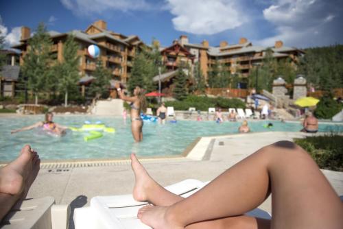 a woman sitting on a chair at a swimming pool at Panorama Mountain Resort - Ski Tip / Tamarack Condos in Panorama