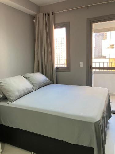 a large bed in a bedroom with two windows at Apto Brooklin ao lado do metro in Sao Paulo