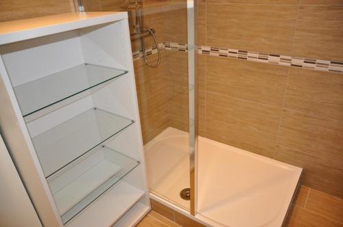 une douche blanche avec des étagères en verre dans une salle de bain dans l'établissement Appartement Reims près des maisons de champagne, à Reims