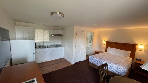 Morgan Inn and Suites Walla Walla في Milton-Freewater: غرفة نوم بسرير ومطبخ مع ثلاجة