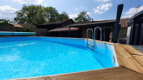 une piscine bleue avec une terrasse en bois dans l'établissement Villa pierre et espace bien etre, à Vertheuil-en-Médoc