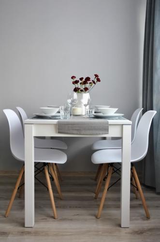 a white dining room table with white chairs at Bohaterów Modlina Point by sleepwell in Nowy Dwór Mazowiecki