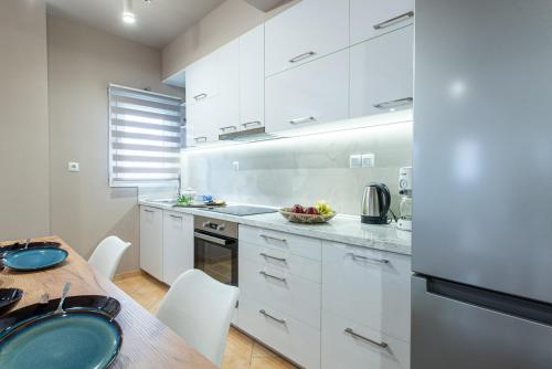 a kitchen with white cabinets and a wooden table at Veria Panorama Luxury Suite with Garden 2 in Veria