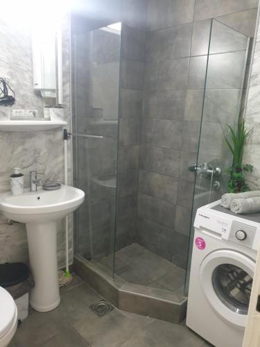 a bathroom with a shower and a sink and a washing machine at Despot Apartmani Niš in Niš