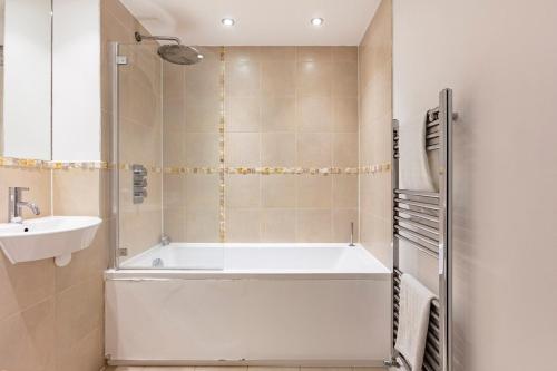 a bathroom with a bath tub and a sink at Hermitage Road Apartment By Morethanstays in London