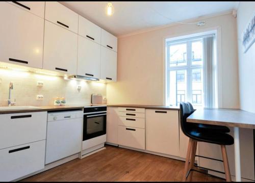 uma cozinha com armários brancos, uma mesa e uma janela em Apartment in Ålesund city center (Storgata) em Ålesund