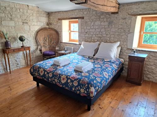 ein Schlafzimmer mit einem Bett und einer Steinmauer in der Unterkunft Le Moulin Etourneau - 3 gîtes avec 2 piscines in Champagnac