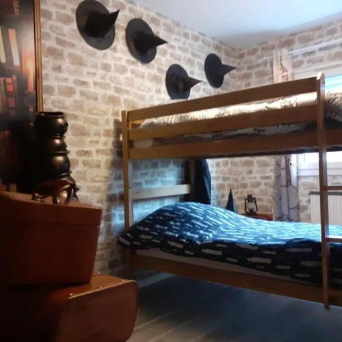 - une chambre avec des lits superposés avec des chapeaux au mur dans l'établissement Appart Aventure, logement entier + escape game !, à Reims