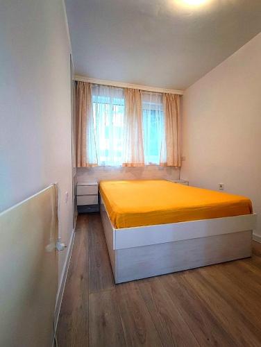 a bedroom with a yellow bed and a window at Апартамент Мелани in Varna City