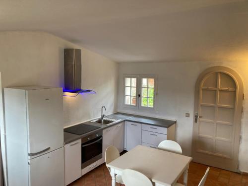- une cuisine avec des appareils blancs, une table et des chaises dans l'établissement Appartement de Charme au calme Parking gratuit, à La Colle-sur-Loup