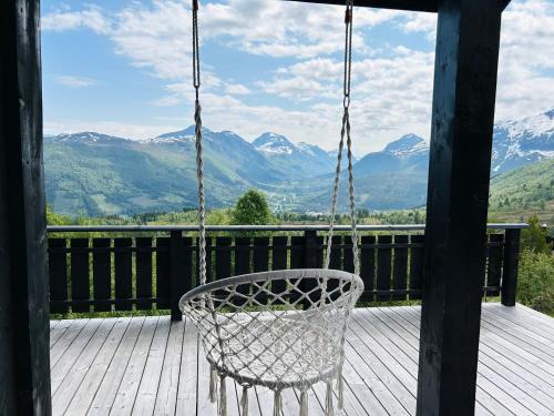 una silla mecedora en un porche con montañas al fondo en Strandafjellet Panorama Lodge - Large Cabin with Majestic Mountain View, en Stranda