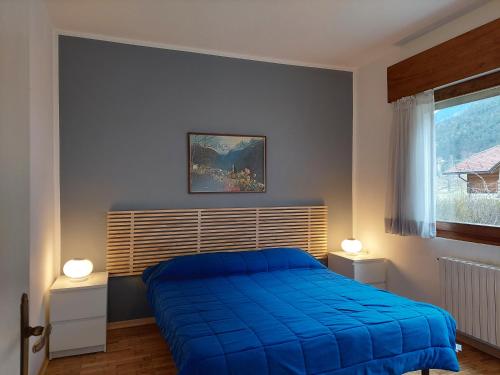 um quarto com uma cama azul e uma janela em La Casetta nelle Dolomiti em Perarolo di Cadore