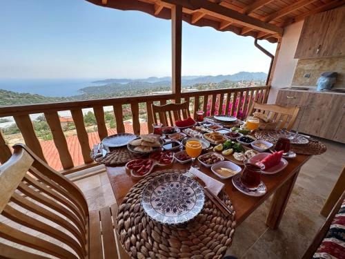 una mesa de madera con comida en la parte superior de un balcón en Istlada Taş Ev Apart - Kekova View, en Antalya
