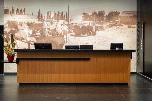 a reception desk in a building with a painting on the wall at Kfar Giladi Hotel in Kefar Gil‘adi