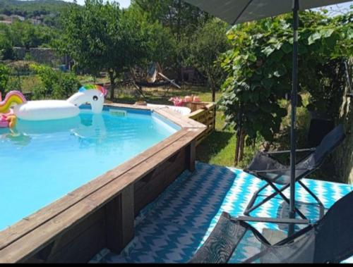 uma piscina com um guarda-sol e duas cadeiras em Grande maison coeur de village piscine jacuzzi em Maureillas