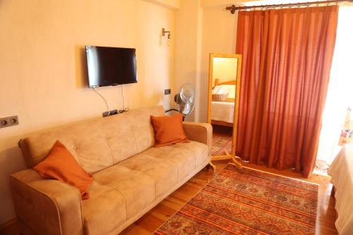 a living room with a couch and a flat screen tv at Istlada Taş Ev Apart - Kekova View in Antalya
