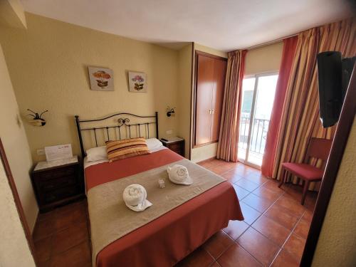 サロブレーニャにあるHostal Jaymaのベッドとバルコニー付きのホテルルーム