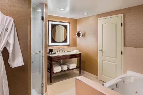 a bathroom with a sink and a tub and a mirror at Sheraton Suites Calgary Eau Claire in Calgary