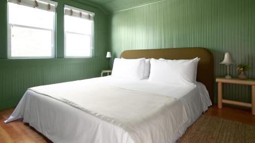 a bedroom with a bed with white sheets and two windows at The Drifthaven at Gearhart in Gearhart