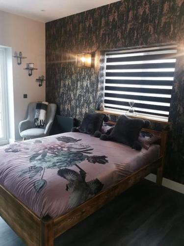 a bedroom with a bed and a chair and a window at Beautiful MASONS HIDEAWAY studio apartment in Bridgend