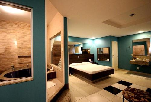 um quarto com uma cama e uma casa de banho com uma banheira em Motel Kalipso em São José