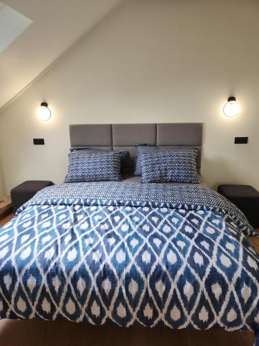 um quarto com uma cama azul e branca com 2 almofadas em Blue Door Apartment Loft em Augustów