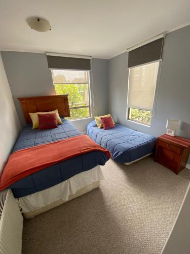 two beds in a room with two windows at Departamento Barrio Poniente in Viña del Mar