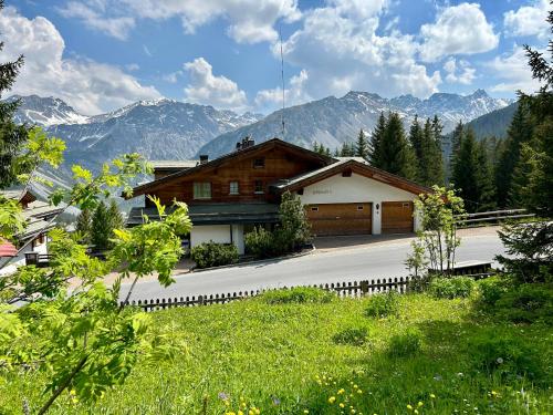 una casa de madera con montañas en el fondo en Höhwald - Maranerhang en Arosa