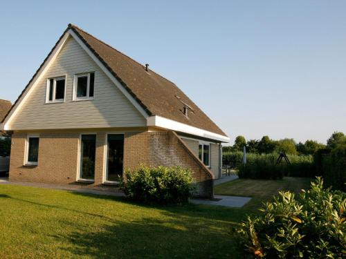 ein Backsteinhaus mit einem Dach auf einem Rasen in der Unterkunft Lush holiday villa at lovely location in Zeewolde in Zeewolde