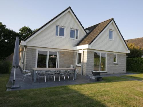 ein Haus mit einer Terrasse mit Stühlen und einem Sonnenschirm in der Unterkunft Lush holiday villa at lovely location in Zeewolde in Zeewolde
