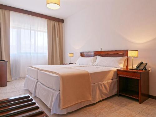 a bedroom with a large bed and a telephone at Hotel Central Santa Maria in Santa Maria