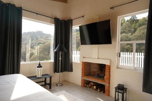 1 dormitorio con chimenea y TV en la pared en Cabaña El Encino III en Real del Monte, en Mineral del Monte