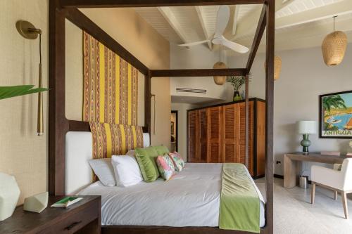 a bedroom with a canopy bed and a desk at Tamarind Hills Resort & Villas in Johnsons Point