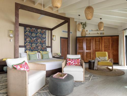 a bedroom with a bed and a couch and chairs at Tamarind Hills Resort & Villas in Johnsons Point