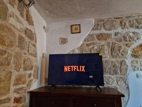 une télévision sur une table dans un mur en pierre dans l'établissement House Riva, à Pirovac