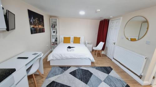 een witte slaapkamer met een bed en een spiegel bij Lovely studio-flat with free parking, free WiFi. in Leeds