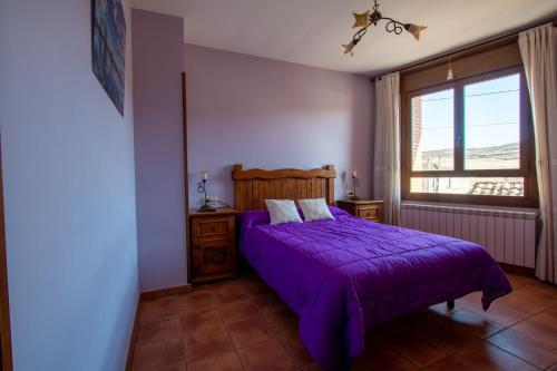 a bedroom with a purple bed and a window at Tirontillana in Dehesa de Cuellar
