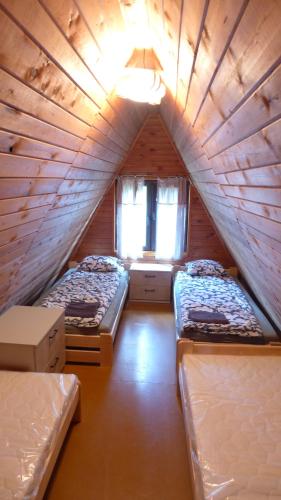 um quarto com três camas numa casa de madeira em Dom Letniskowy nad Krutynią em Spychowo